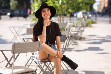 Beautiful young woman in stylish black hat on city street