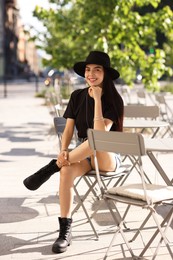 Photo of Beautiful young woman in stylish black hat on city street