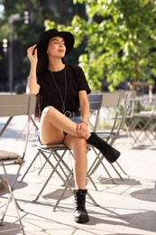 Photo of Beautiful young woman in stylish black hat on city street