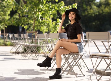 Photo of Beautiful young woman in stylish black hat on city street