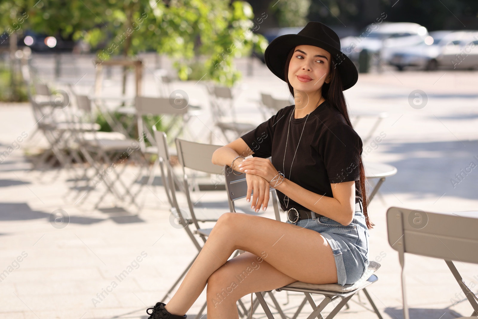 Photo of Beautiful young woman in stylish black hat on city street