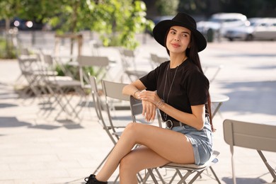 Beautiful young woman in stylish black hat on city street