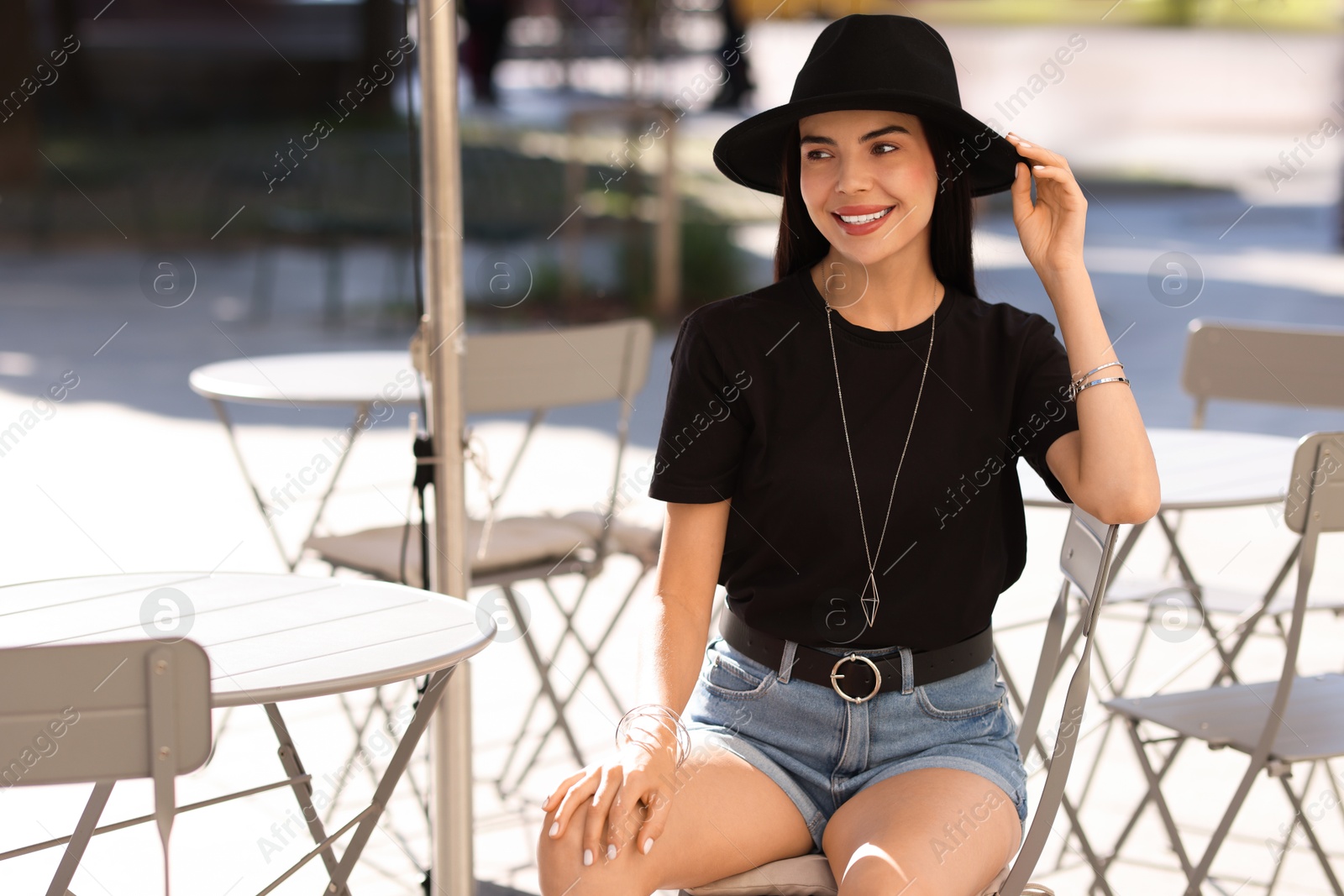 Photo of Beautiful young woman in stylish black hat on city street