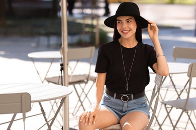 Photo of Beautiful young woman in stylish black hat on city street