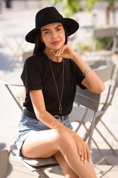 Beautiful young woman in stylish black hat on city street