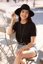 Beautiful young woman in stylish black hat on city street