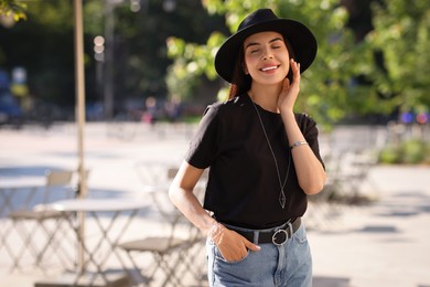 Beautiful young woman in stylish black hat on city street