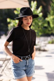 Photo of Beautiful young woman in stylish black hat on city street