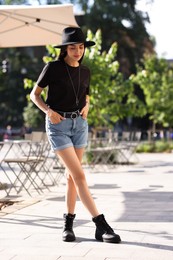 Beautiful young woman in stylish black hat on city street