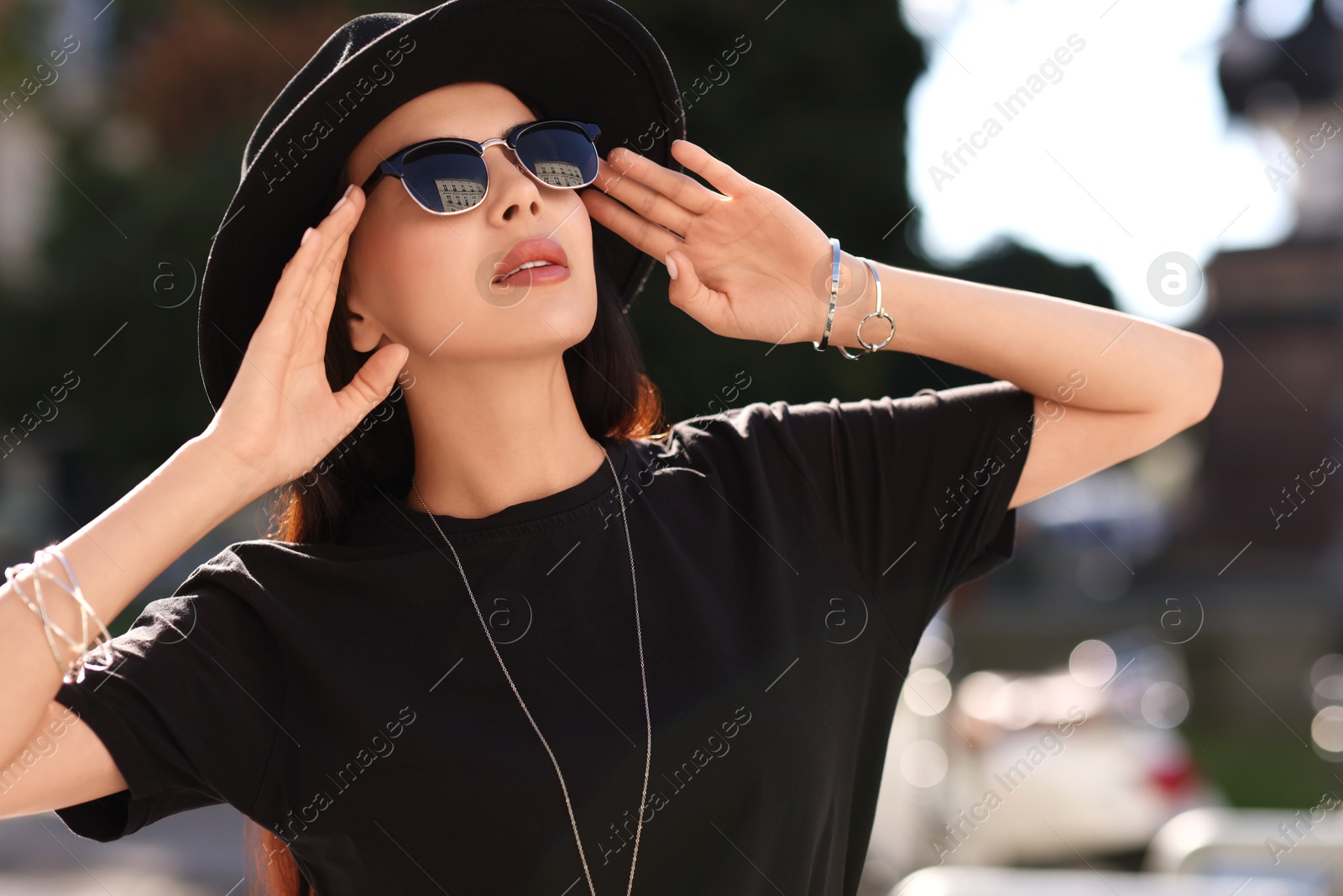 Photo of Young woman in stylish black hat and sunglasses outdoors