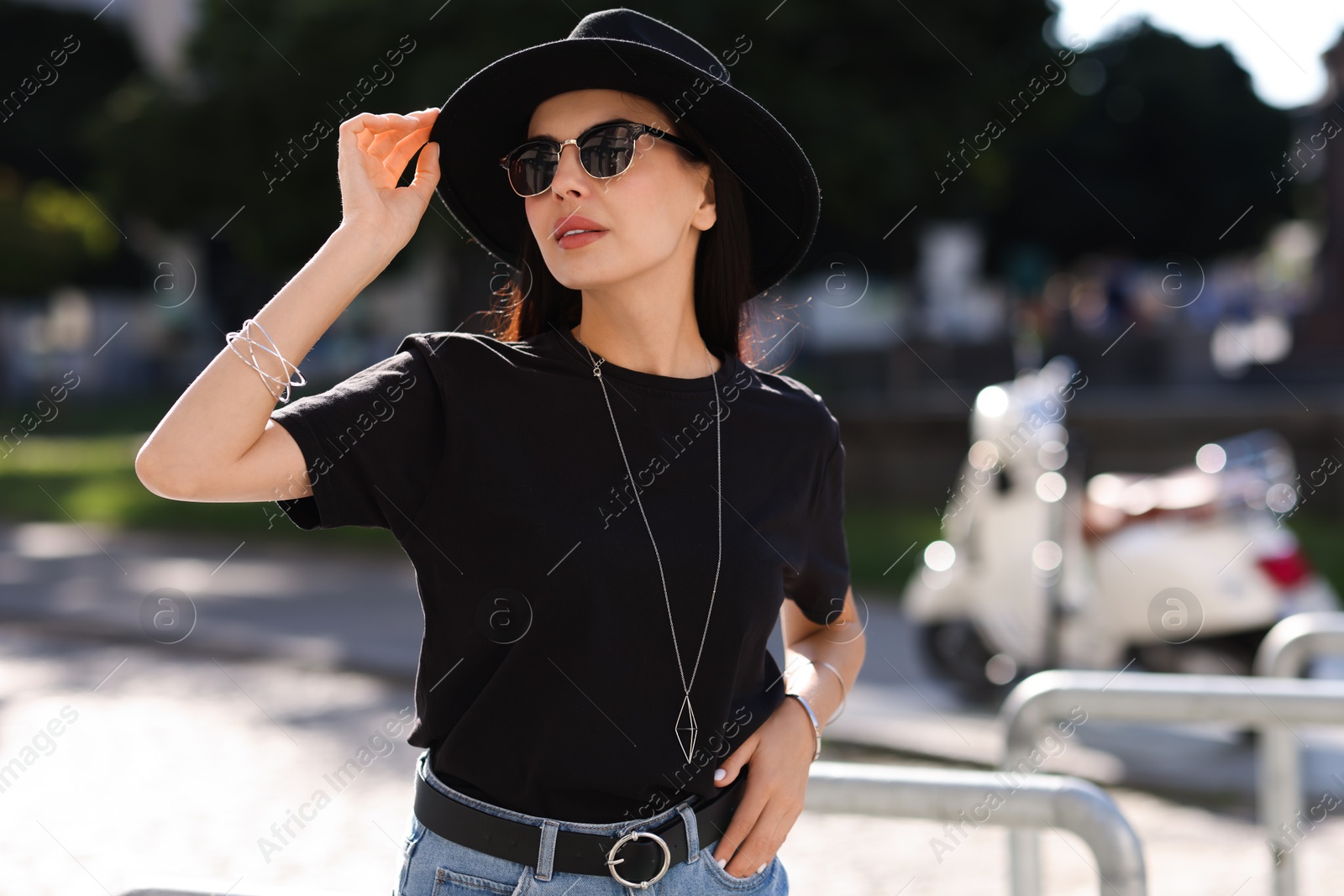 Photo of Young woman in stylish black hat and sunglasses on city street