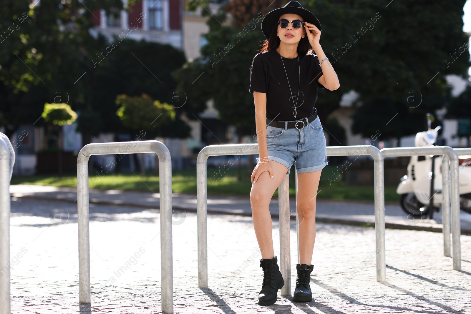 Photo of Young woman in stylish black hat and sunglasses on city street