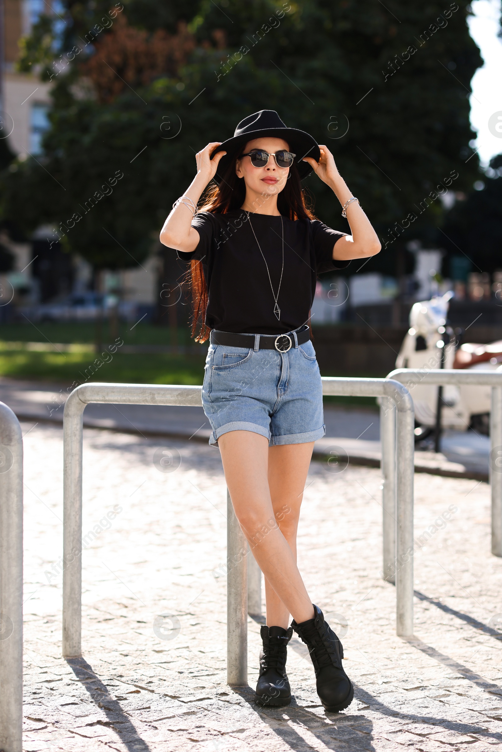 Photo of Young woman in stylish black hat and sunglasses on city street