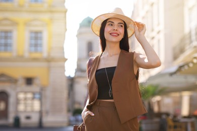 Beautiful young woman in stylish hat on city street