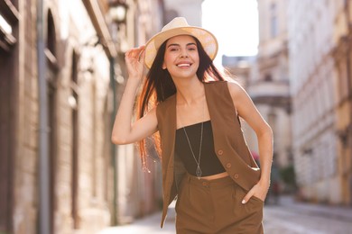 Beautiful young woman in stylish hat on city street