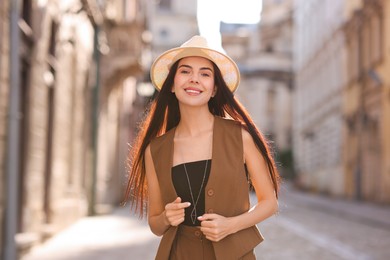 Beautiful young woman in stylish hat on city street