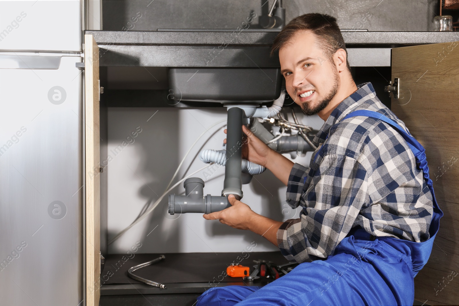 Photo of Professional plumber fixing piping system at home