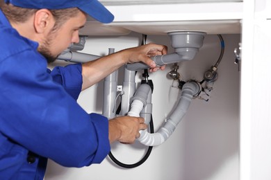 Professional plumber fixing piping system at home