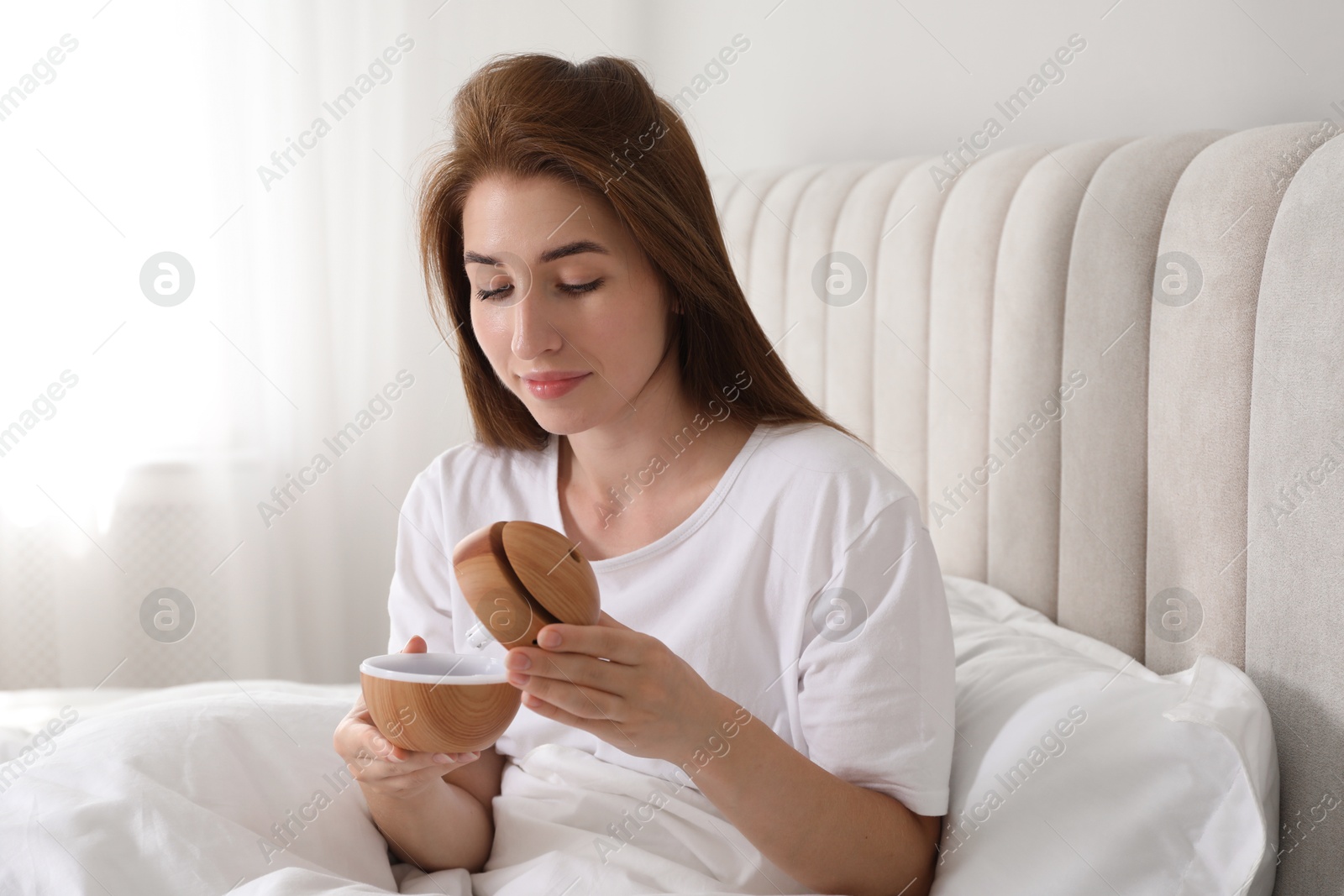 Photo of Woman with essential oil aroma diffuser at home