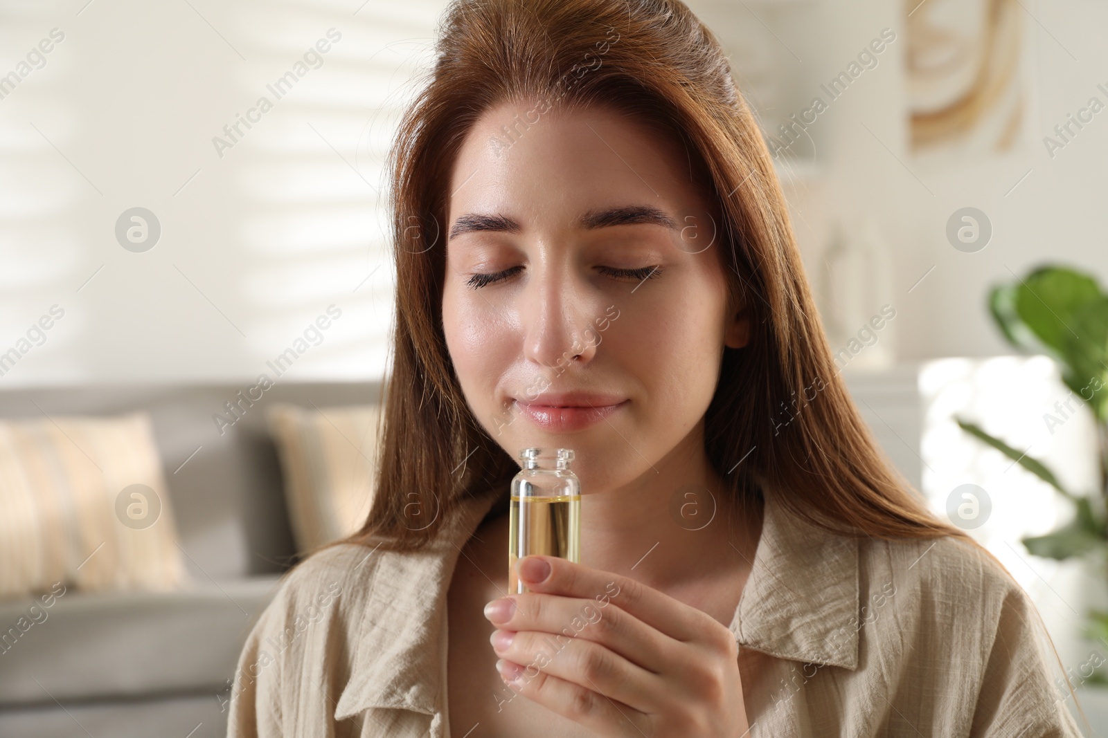 Photo of Woman with bottle of essential oil at home