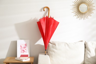 Photo of Red umbrella drying on sofa at home