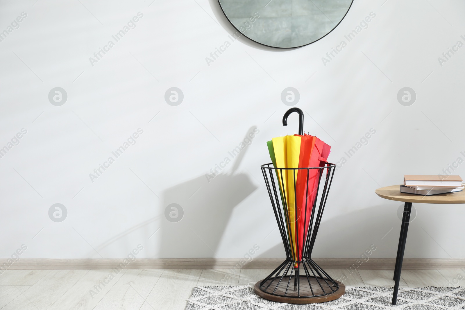 Photo of Colorful umbrella in stand near light wall. Space for text