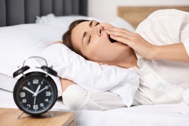 Sleepy woman waking up in bed at lunch time