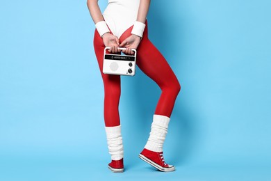 Photo of Aerobics. Woman with radio receiver on light blue background, closeup