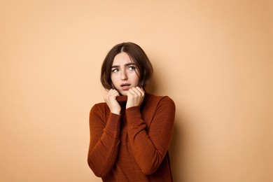 Portrait of scared woman on beige background