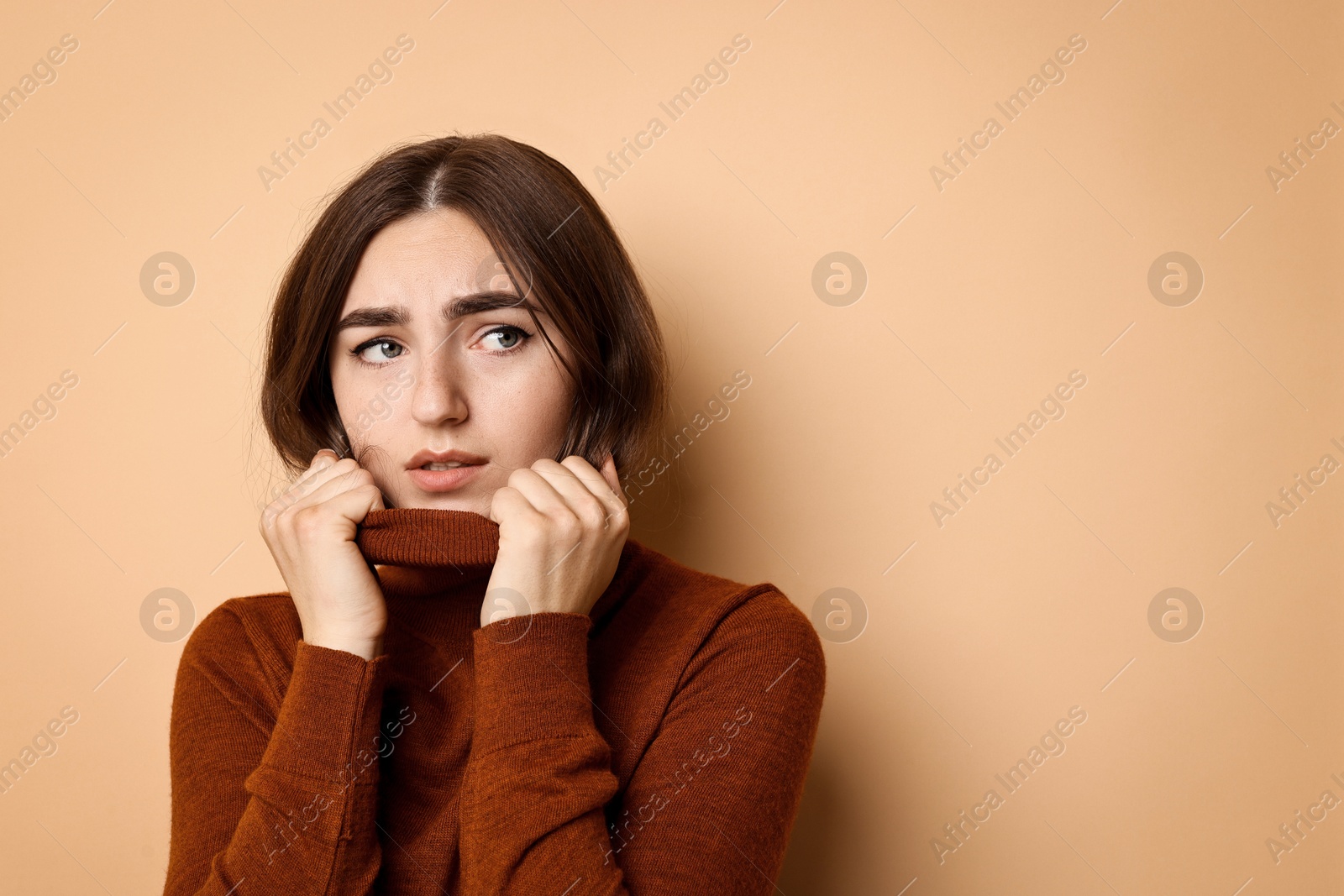 Photo of Portrait of scared woman on beige background. Space for text