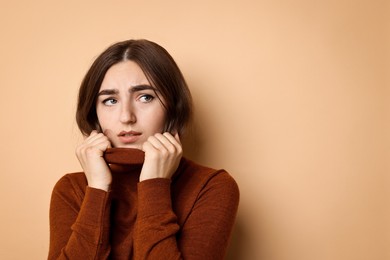 Photo of Portrait of scared woman on beige background. Space for text