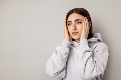 Portrait of scared woman on light background. Space for text