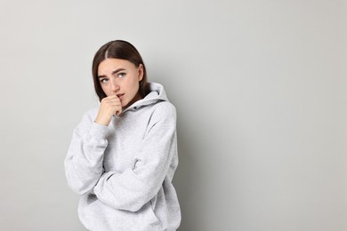 Portrait of scared woman on light background. Space for text