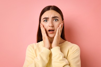 Portrait of scared woman on pink background