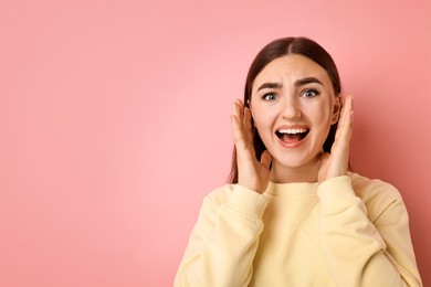 Photo of Portrait of scared woman on pink background. Space for text