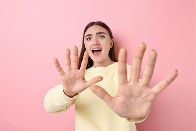 Portrait of scared woman on pink background