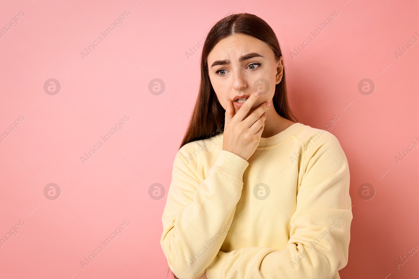 Photo of Portrait of scared woman on pink background. Space for text