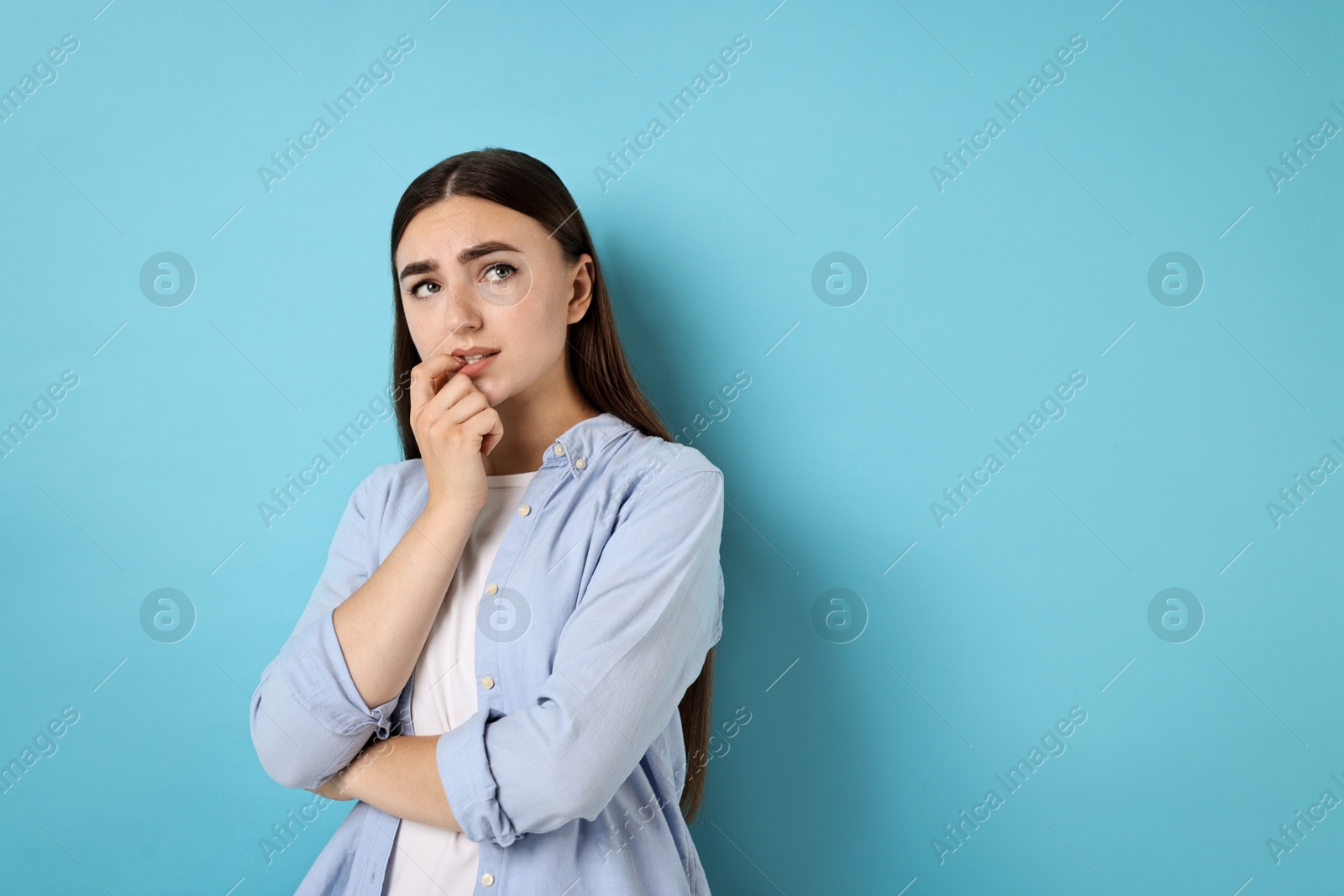 Photo of Portrait of scared woman on light blue background. Space for text