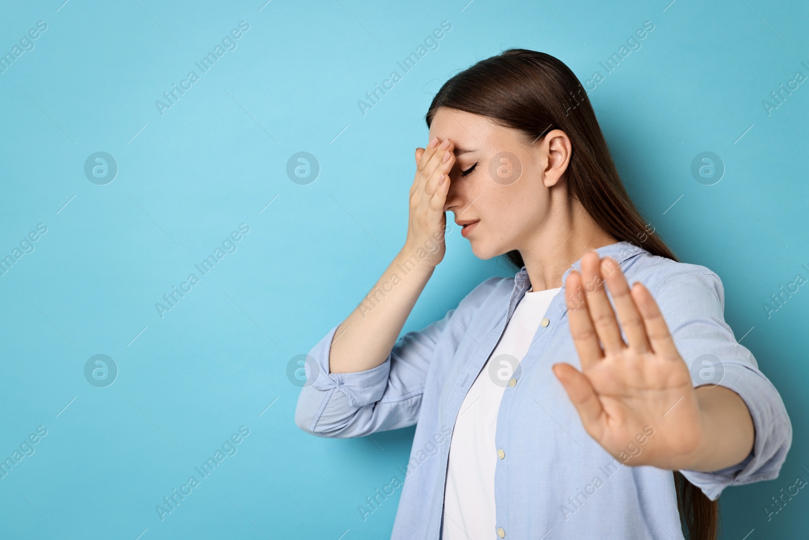 Photo of Portrait of scared woman on light blue background. Space for text