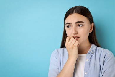 Photo of Portrait of scared woman on light blue background. Space for text