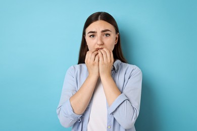 Portrait of scared woman on light blue background