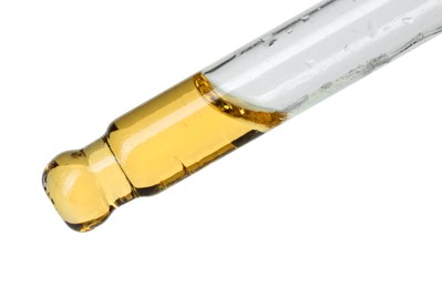 Photo of Dripping essential oil from pipette on white background