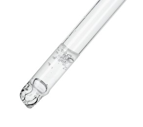 Dripping cosmetic serum from pipette on white background