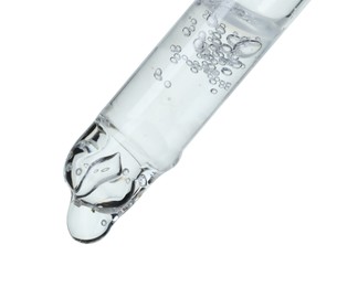 Dripping cosmetic serum from pipette on white background