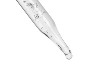 Dripping cosmetic serum from pipette on white background