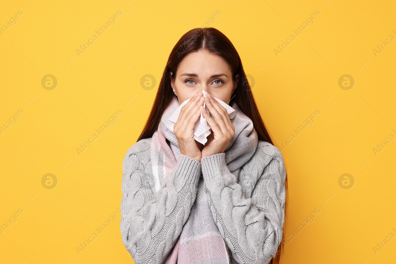 Photo of Sick woman with tissue on orange background. Cold symptoms