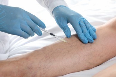 Photo of Varicose veins treatment. Doctor giving injection to patient indoors, closeup