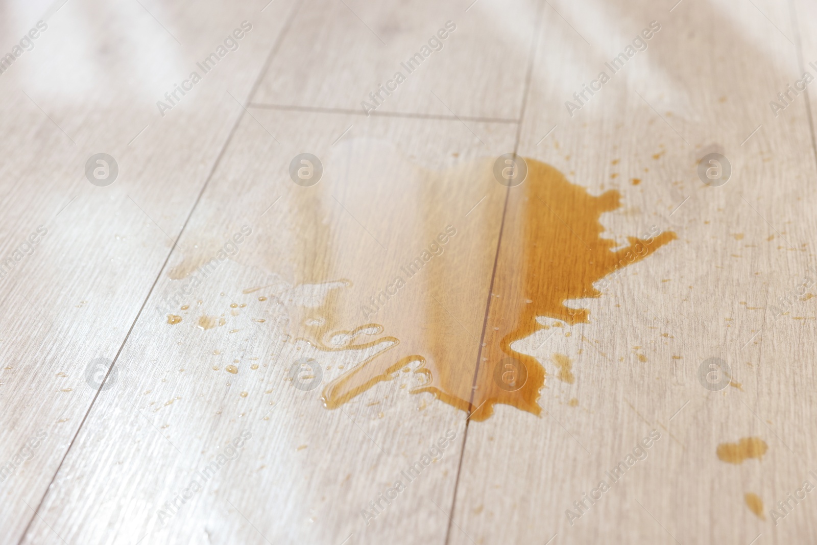 Photo of Puddle of spilled drink on wooden floor, closeup