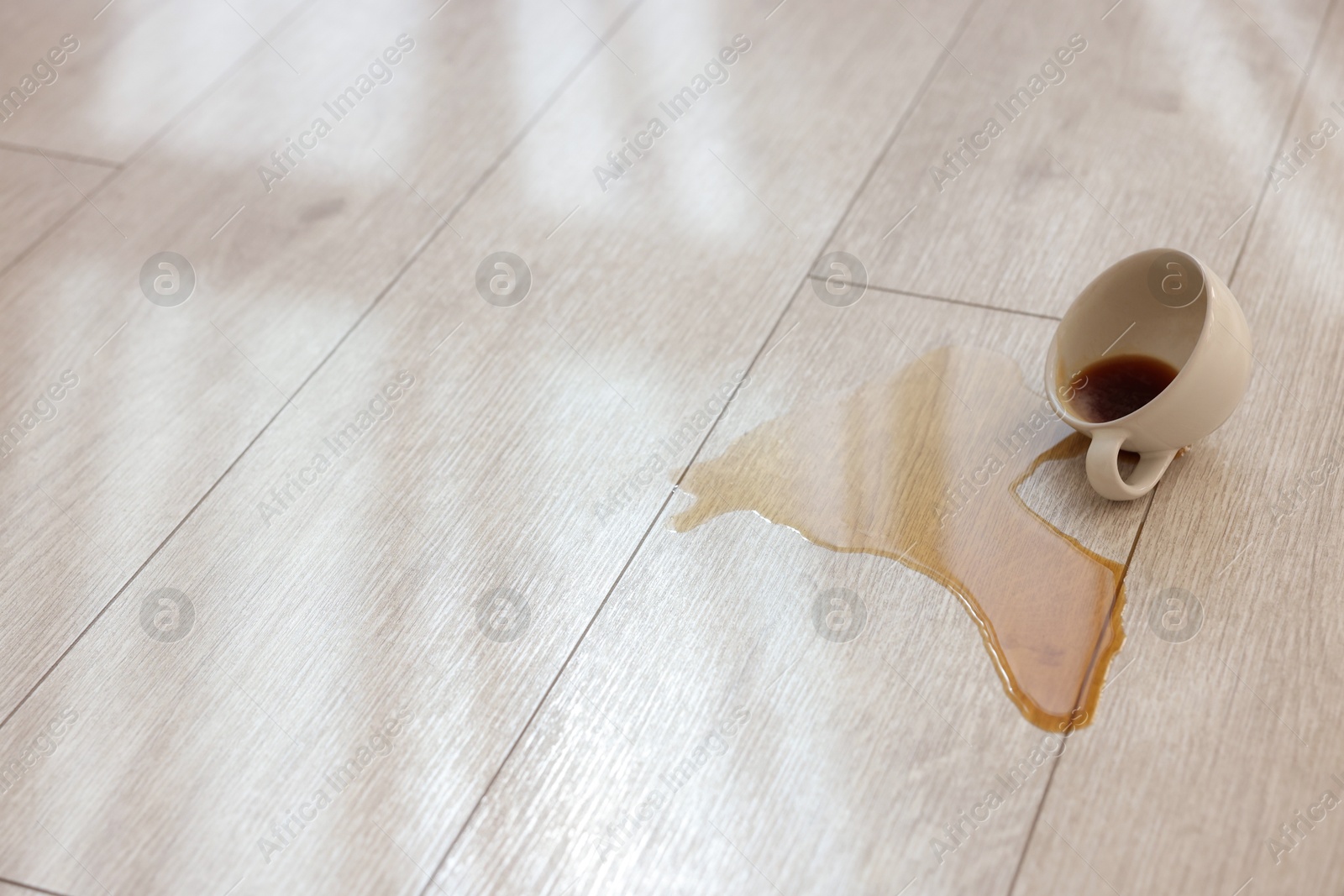 Photo of Cup with spilled drink on wooden floor. Space for text