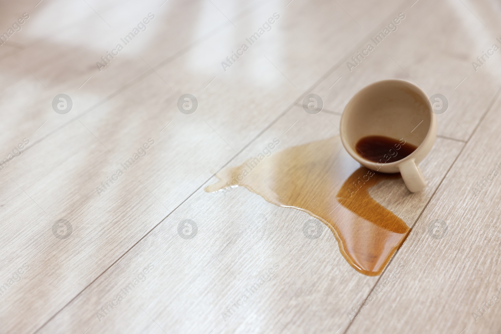 Photo of Cup with spilled drink on wooden floor. Space for text